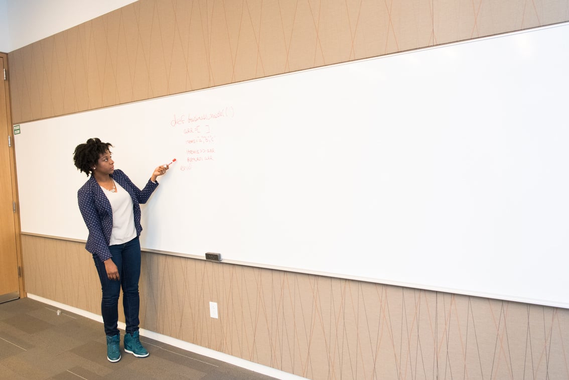 Woman Wearing Black Blazer Holding Pen Pointing White Marker Board